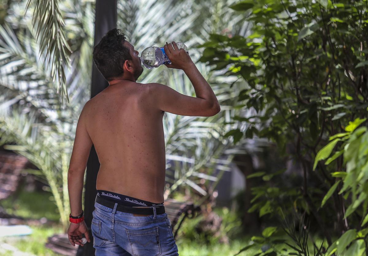 Un ciudadano combate las altas temperaturas hidratándose en la sombra de un parque.
