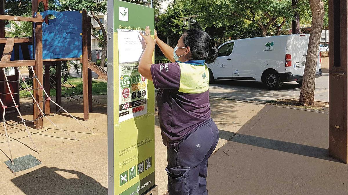 Una trabajadora de Parcs i Jardins de Palma coloca un cartel con las nuevas restricciones.