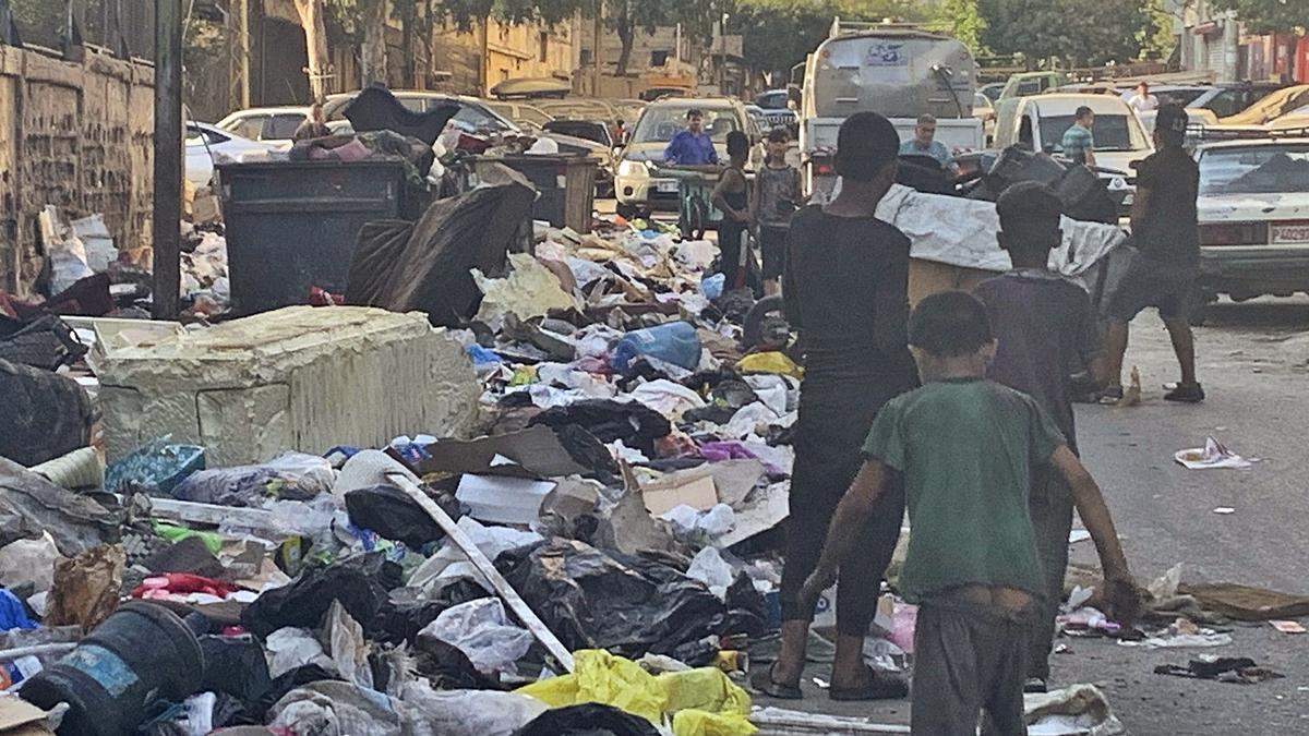 Un grup de persones busca menjar entre les escombraries al camp de refugiats de Shatila. | NOEMÍ JABOIS