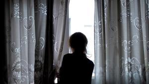 Una mujer observa a través de la ventana de su vivienda, en la que permanece confinada, en Ourense, el 19 de abril.