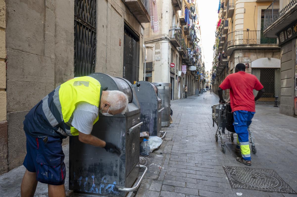 Un operario realiza trabajos de mantenimiento de contendores en el barrio del Raval.