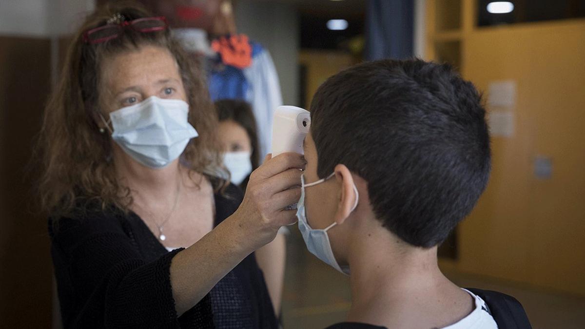 Una profesora del Institut Escola Antaviana de Barcelona comprueba la temperatura de un alumno, el pasado 15 de junio.