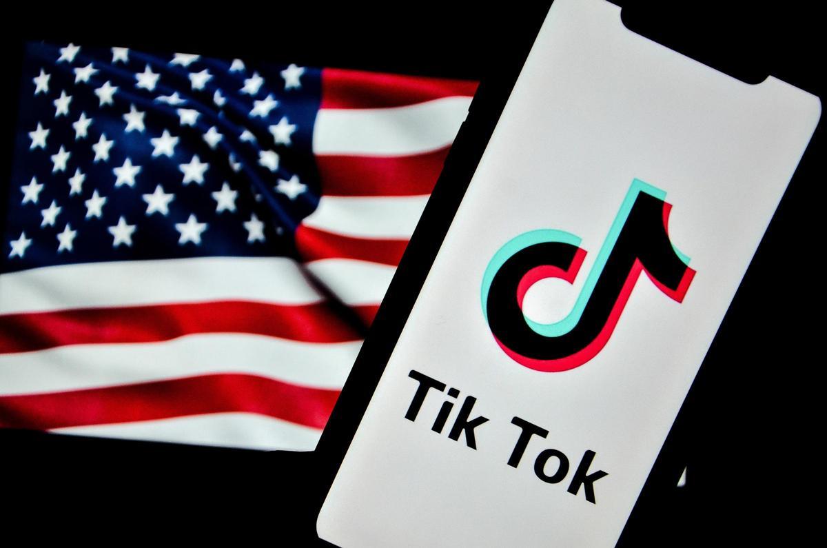 El logotipo de TikTok aparece en la pantalla de un teléfono con la bandera de Estados Unidos de fondo