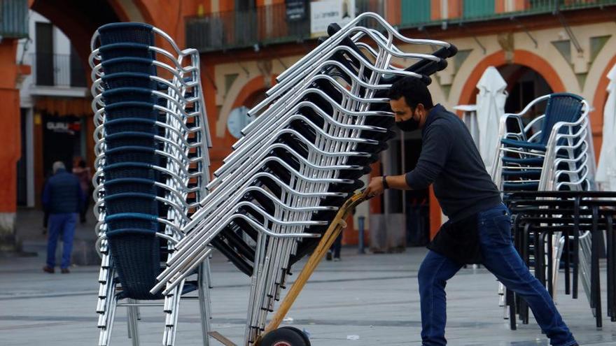 Un trabajador de la hostelería recoge una terraza en Córdoba.