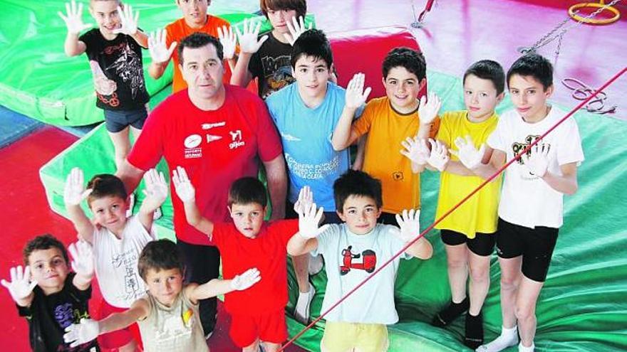José Luis González, «Uli», posa con gimnastas del Grupo Covadonga, que muestran sus manos embadurnadas con magnesia. / marcos león