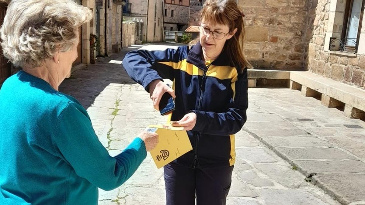 Una cartera rural entrega un certificado a una vecina.