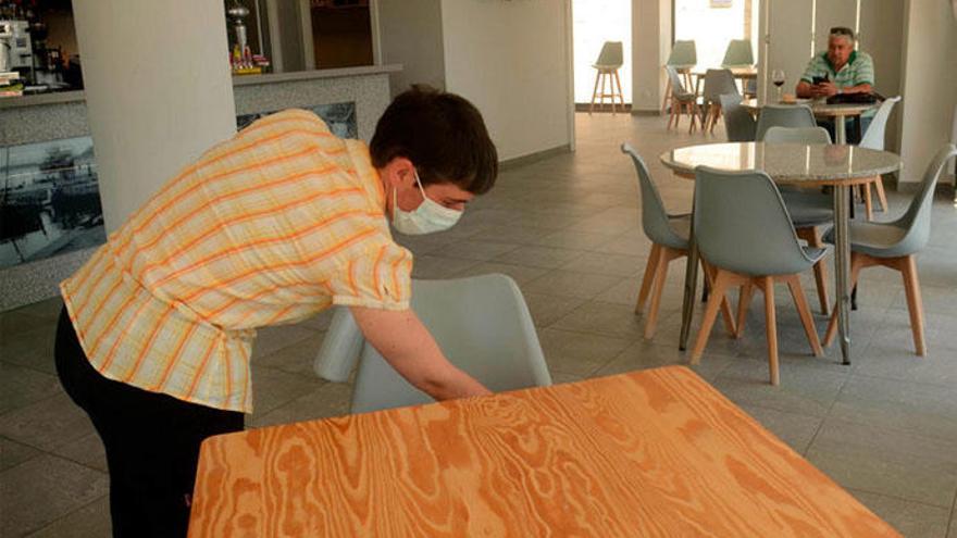 Una mujer desinfecta una silla en una cafetería de Vilanova.