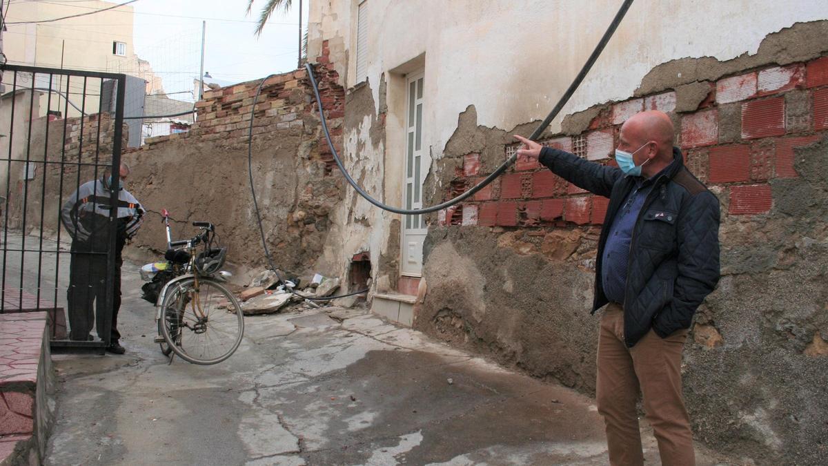 El edil de IU señala las canalizaciones de agua que sobrevuelan las calles.