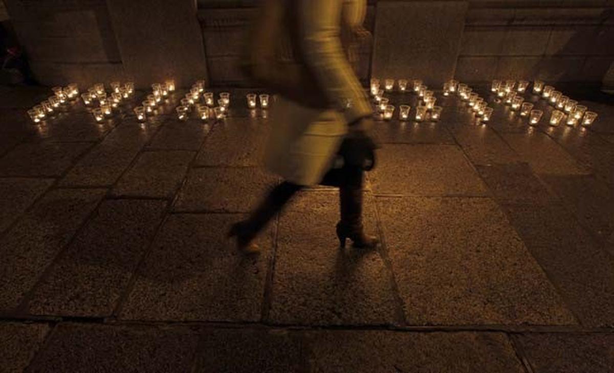 Un peatón camina cerca de unas velas que se encuentran frente a los edificios del Gobierno en Dublín (Irlanda). Las velas forman los años 1916-2010, y fueron encendidas por unos manifestantes que piensan que el actual gobierno ha traicionado a los líderes que lucharon en la Guerra Civil de 1916 de  la República de Irlanda.