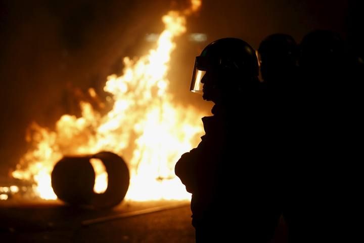 Riot police guard a junction with a fire set by protesters at Mongkok district in Hong Kong