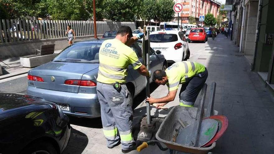 Dos operarios colocan señales en la calle Orillamar, que quedará cerrada al tráfico el lunes.