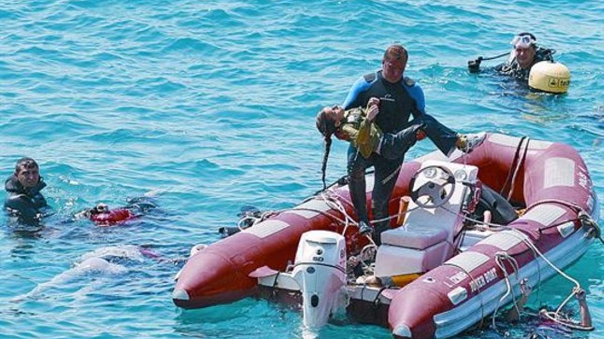 Un submarinista recupera del mar el cuerpo de una niña fallecida en el naufragio, ayer, cerca de Samos.