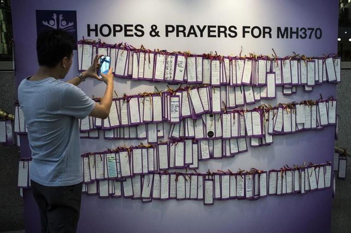 Un jove fotografia un mur amb missatges de suport als passatgers del vol de Malaysia Airlines desaparegut, aquest dilluns en un centre comercial de Kuala Lumpur.