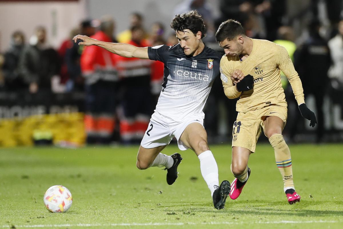 CEUTA, 19/01/2023.- El defensa del Ceuta Juan Gutiérrez (i) trata de jugar un balón ante Ferrán Torres, del FC Barcelona, durante el partido de octavos de final de Copa del Rey que AD Ceuta y FC Barcelona disputan este jueves en el estadio Alfonso Murube de la ciudad autónoma de Ceuta. EFE/José Manuel Vidal