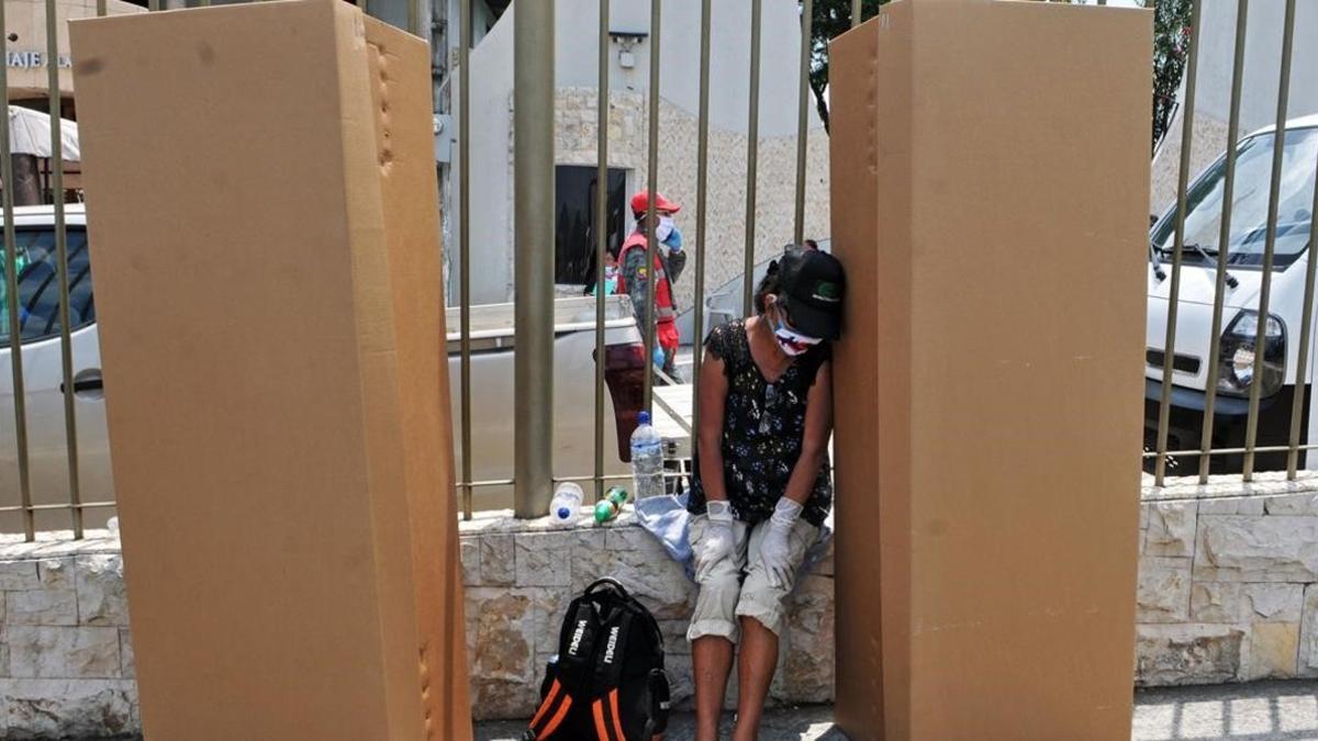 Una mujer llora a un familiar junto a unos ataúdes de cartón en Guayaquil.