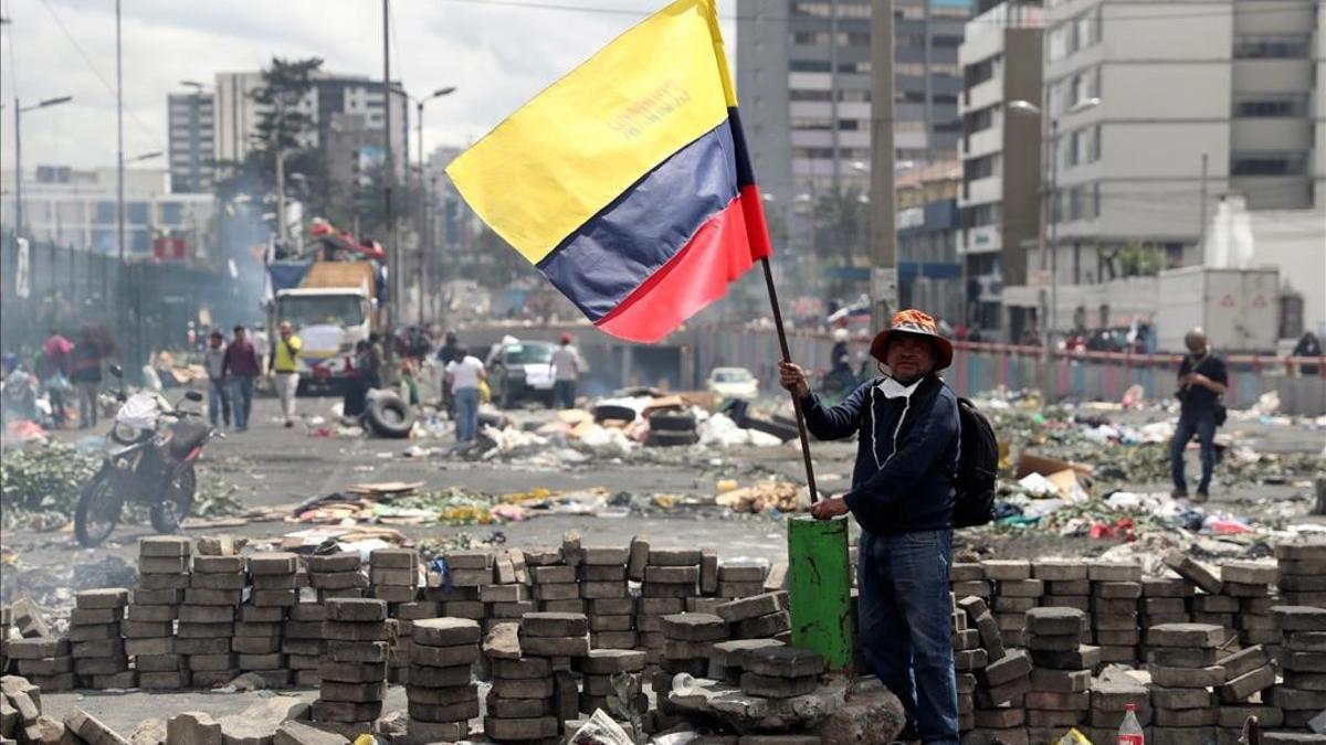 Un hombre sostiene una bandera ecuatoriana tras una protesta por las calles de Quito.