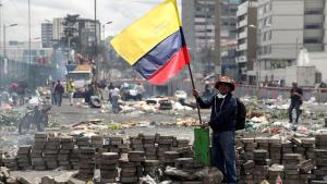 Un hombre sostiene una bandera ecuatoriana tras una protesta por las calles de Quito.