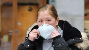 Una mujer se pone una mascarilla.