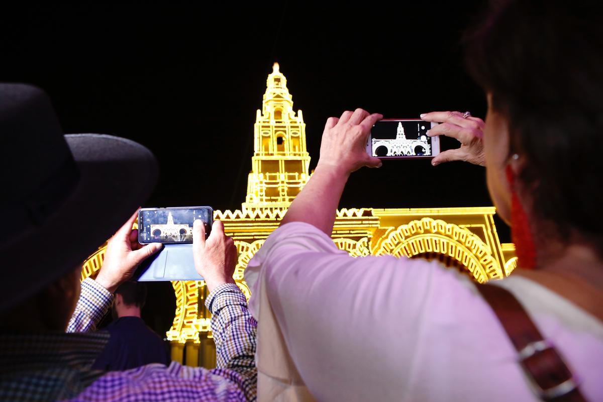 Dos mujeres hacen fotos a la portada de la Feria tras el alumbrado, en la edición del 2019.