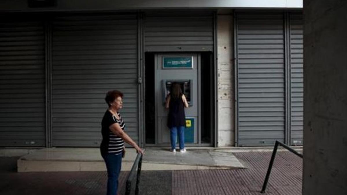 Una mujer retira dinero de cun cajero ayer en Atenas tras tres semanas de control de capitales.