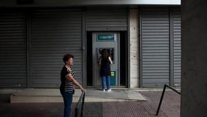 Una mujer retira dinero de cun cajero ayer en Atenas tras tres semanas de control de capitales.