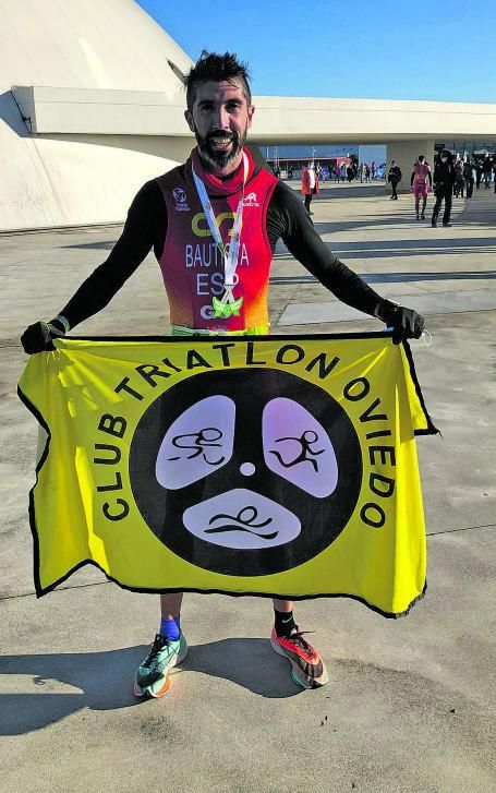 Juan Expósito, doble campeón del mundo, con una bandera del Club Triatlón Oviedo. | LNE