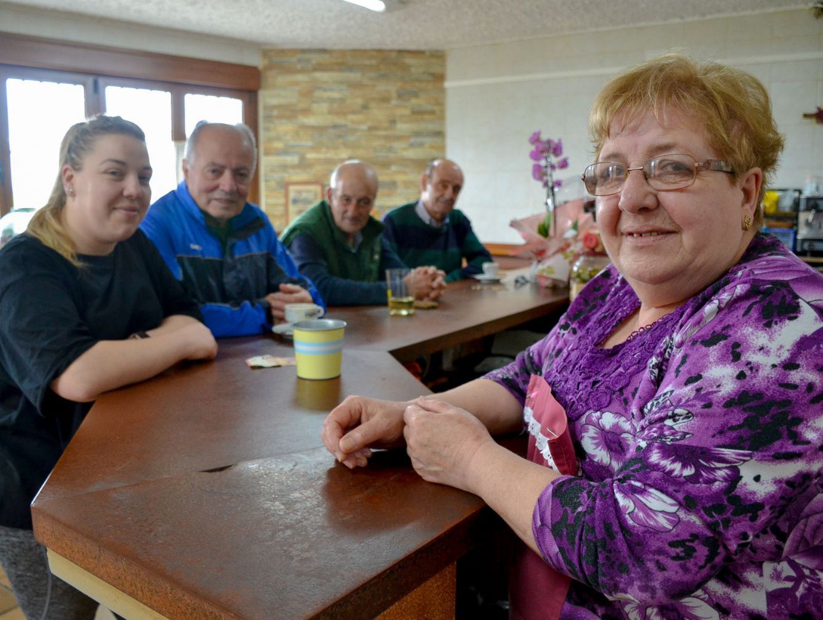 En primer término, Marlene Martínez y, tras la barra, Isabel Casielles, junto a tres de sus clientes: Jorge Onís, José Luis Villanueva y José Manuel Bermúdez, en el chigre Casa Fredín en Valdesoto (Siero).