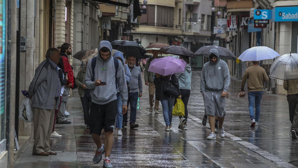 Varias personas caminando bajo la lluvia hace unos días en el centro de Elche.