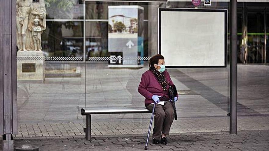 Una mujer, sola en una parada de autobús.