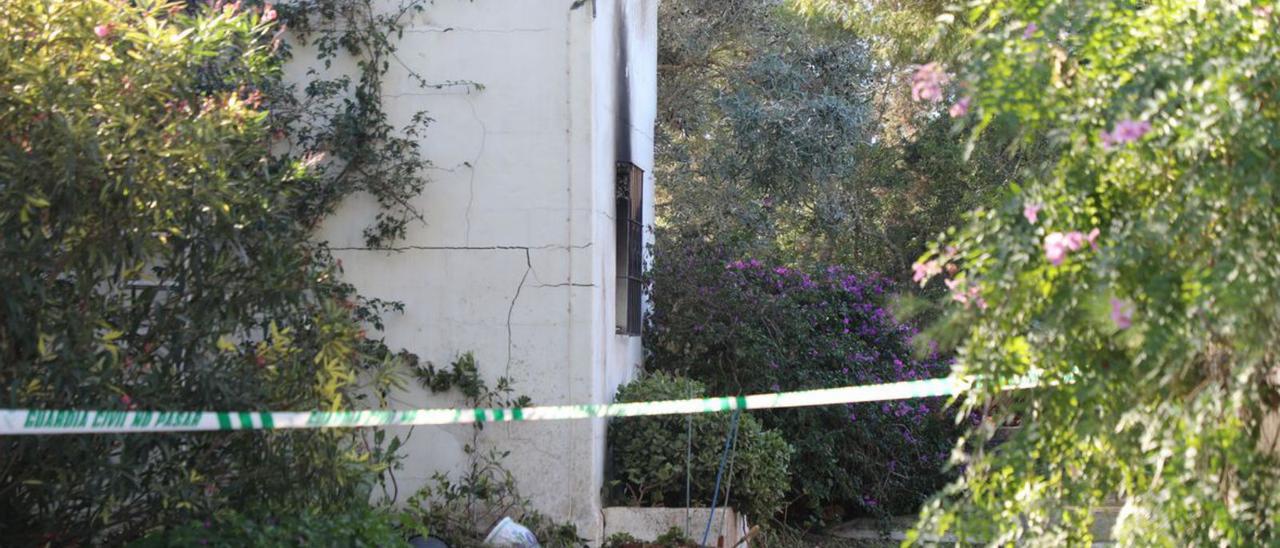 El coche de la Guardia Civil en el aparcamiento de la vivienda. A la derecha, detalle de la parte más dañada de la casa incendiada. | C.C.