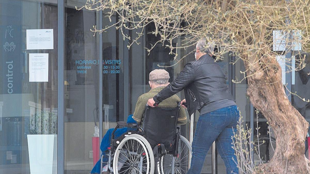 Una mujer empuja la silla de ruedas de un anciano