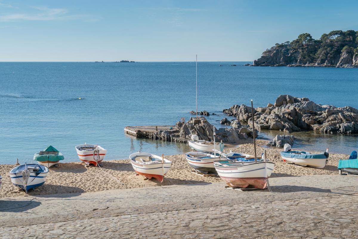 Barcos de pesca tradicionales del Mediterráneo en la playa de arena con el telón de fondo del pueblo blanco. Calella de Palafrugell