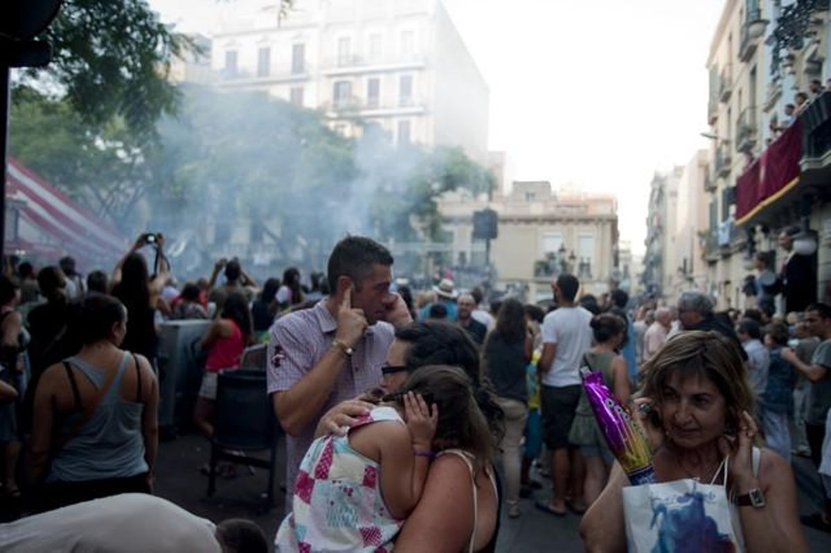 Els diables i els trabucaires fan que la gent es tapi les orelles, a la plaça de la Vila de Gràcia.