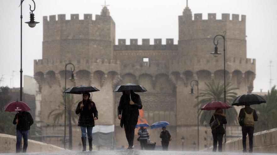 Varios viandantes se protegen de la lluvia con paraguas.