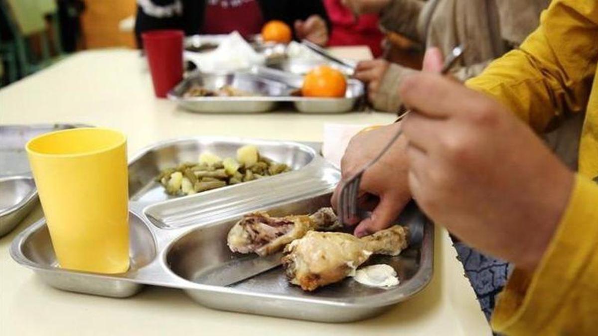 Un niño desmenuza un muslo de pollo en el comedor escolar.