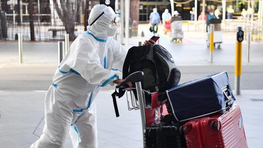 Un viajero viste un traje protector a su llegada al aeropuerto de Sidney.