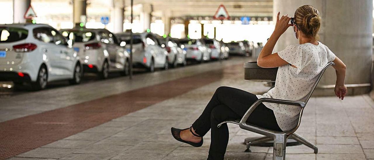 Una mujer observa la gran cantidad de taxis en la parada del aeropuerto que aguardan la entrada de servicios.