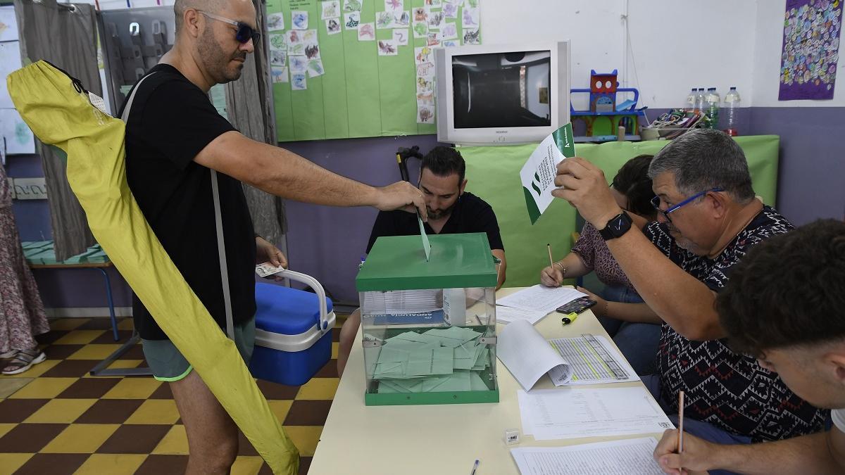 Sin soltar la sombrilla y la nevera, este ciudadano deposita su voto el domingo 19J, antes de irse a la playa, en Almería.