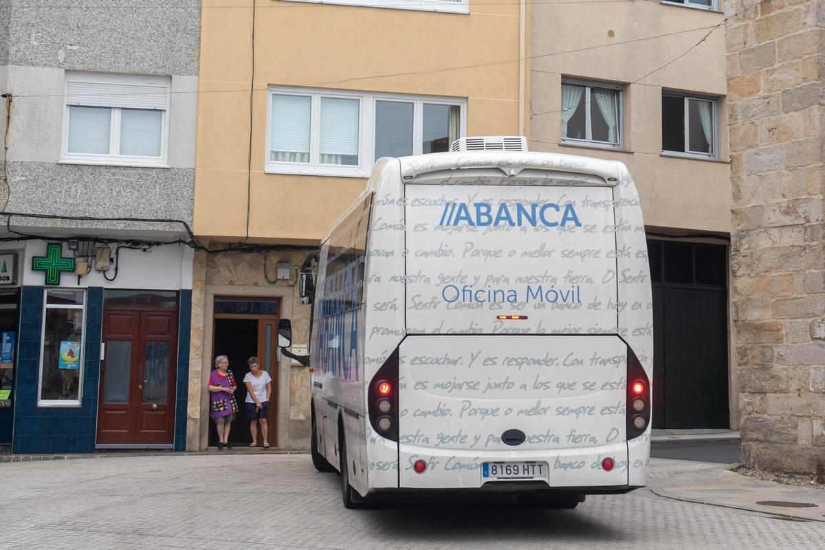 Dos vecinas frente al autobús de Abanca a su paso por Caión.