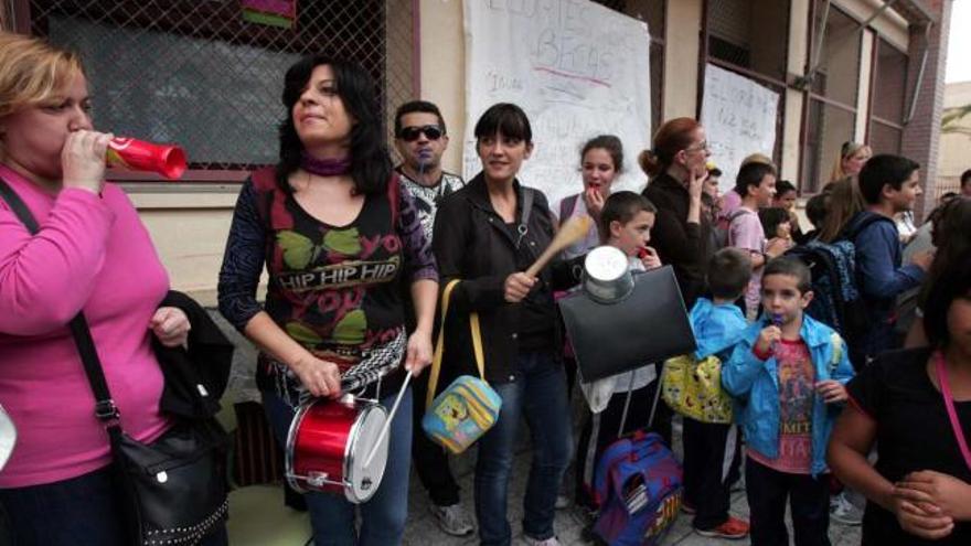Madres del colegio público Víctor Pradera de Elche, ayer, a la puerta del centro con cacerolas y pitos por las becas de comedor.