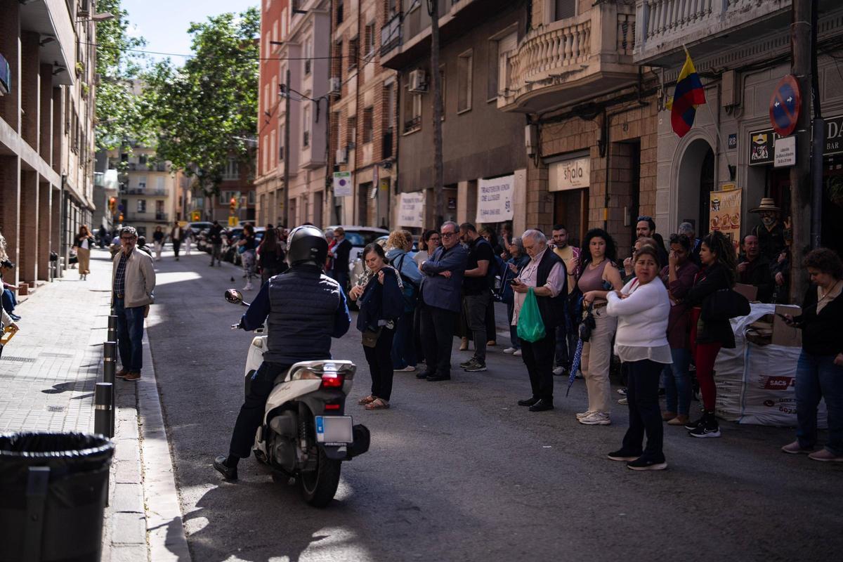 Una moto junto a la aglomeración de padres y familiares en la entrada de la escuela Pàlcam de Barcelona al finalizar la jornada escolar