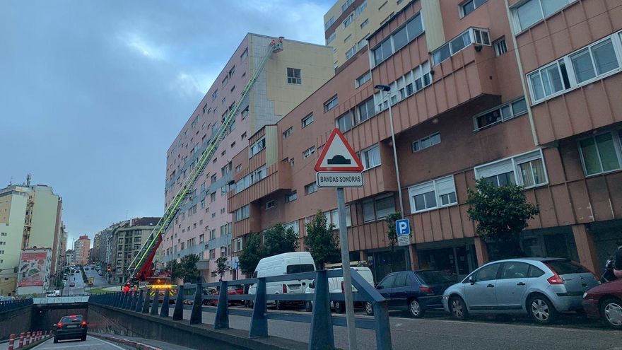 Los bomberos retirando las planchas desprendidas de un edificio de Travesía de Vigo.