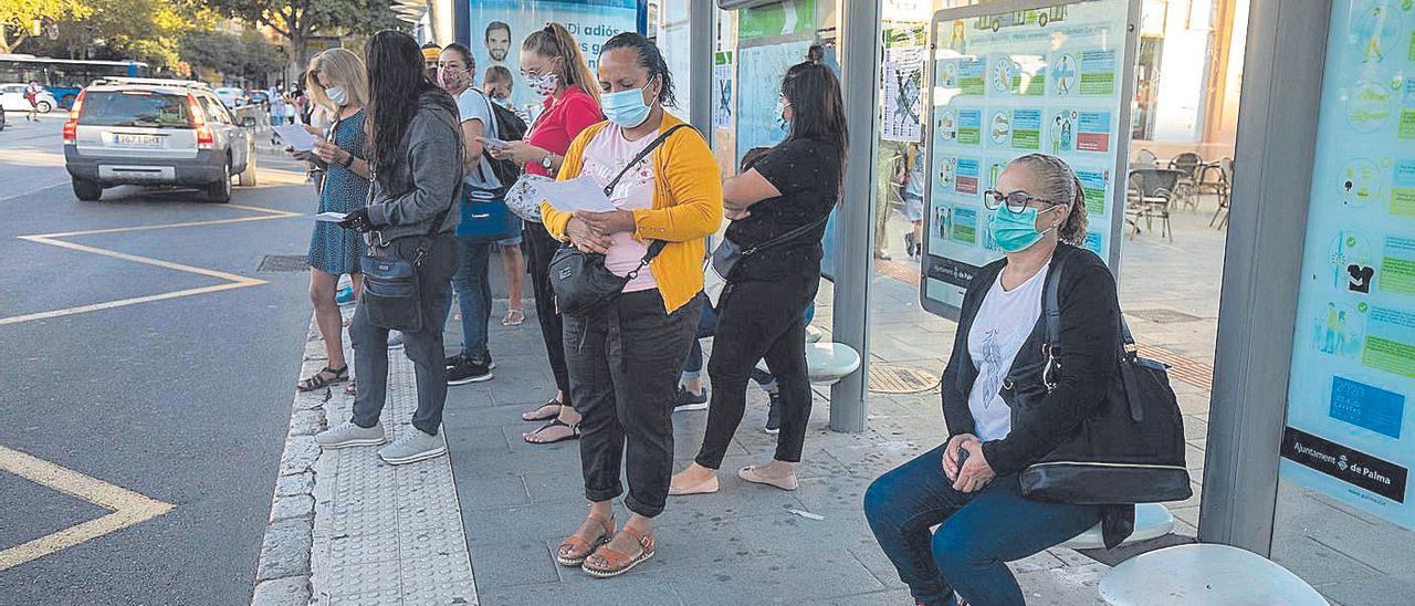 Usuarios de la EMT aguardando en una parada la llegada de un autobús de servicio.