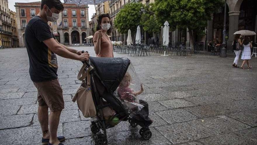 Una pareja pasa por delante de una terraza vacía con una niña.