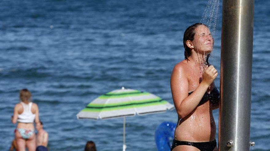 Una joven se refresca en una ducha en una playa de Málaga capital.