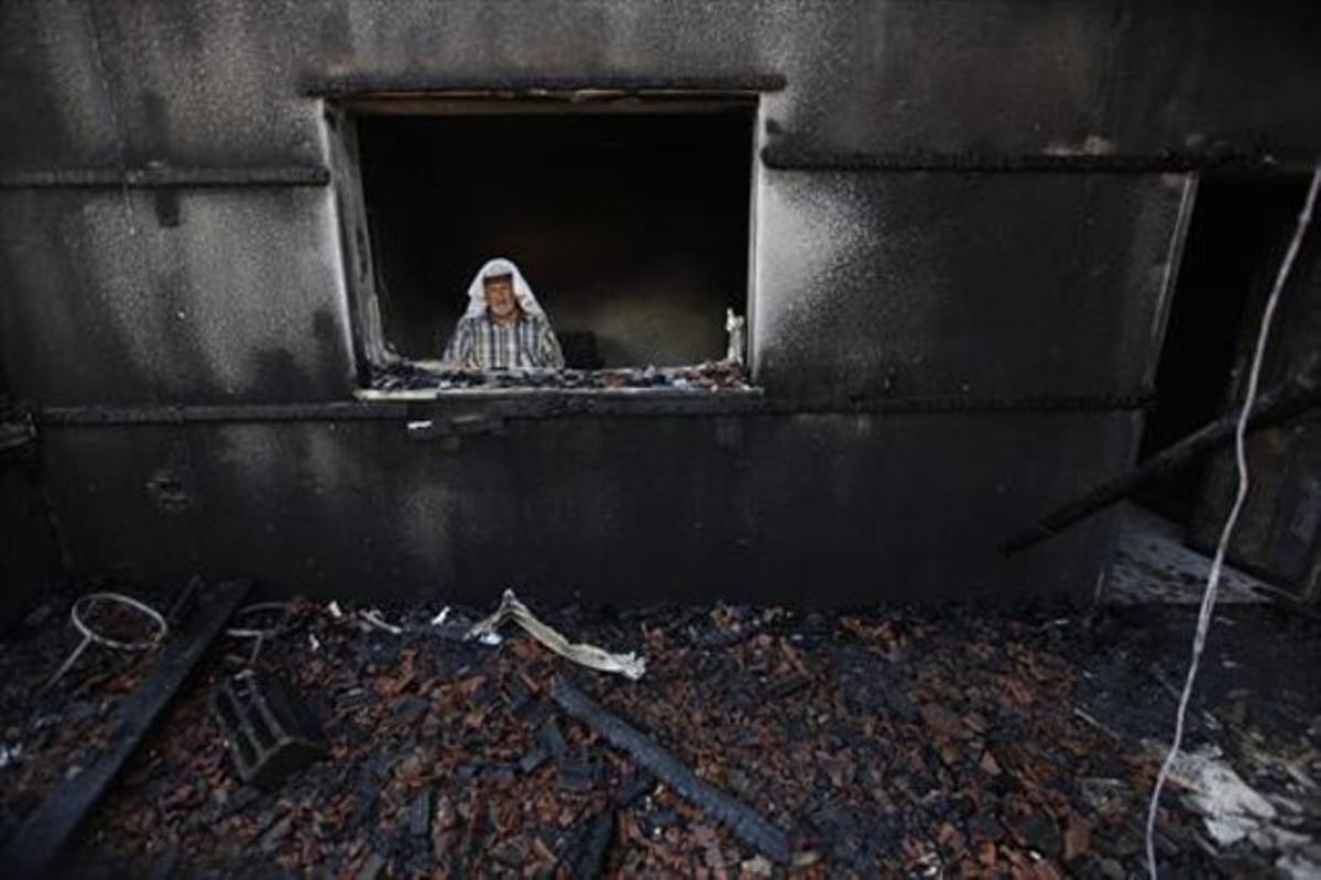 Un home inspecciona la casa atacada pels colons on va morir cremat el nen de 18 mesos a la localitat palestina de Duma.