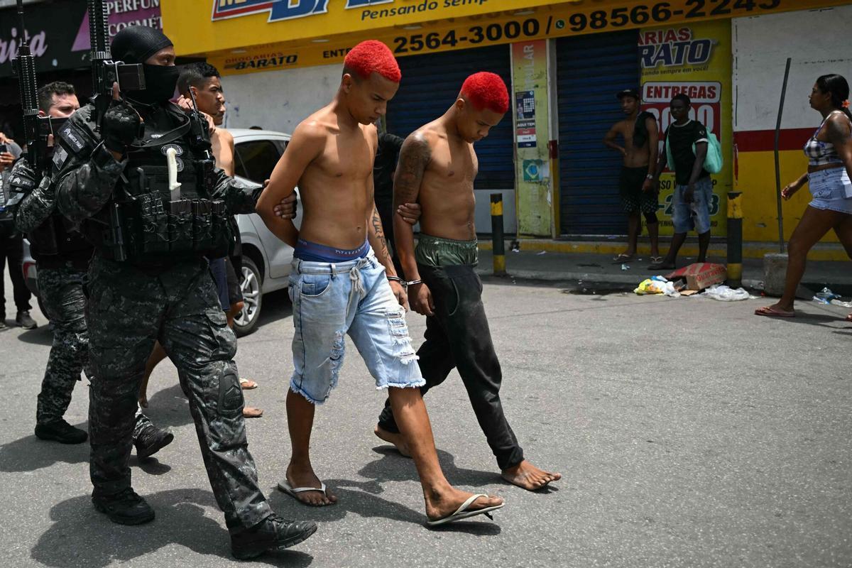 TOPSHOT - Police officers escort suspects arrested during the Operacao Contencao (Operation Containment) out of the Vila Cruzeiro favela, in the Penha complex, in Rio de Janeiro, Brazil, on October 28, 2025. At least 2,500 agents took part in an operation to arrest drug traffickers from the Comando Vermelho (CV), which resulted in, at least, 18 suspects and several police officers dead. (Photo by Mauro PIMENTEL / AFP)