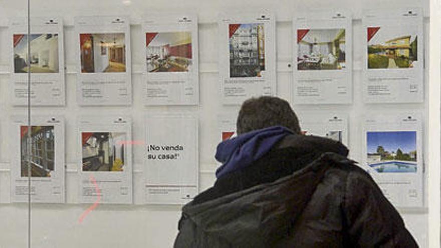 Un hombre observa la oferta del escaparate de una inmobiliaria.