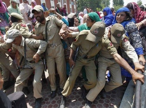Indian policemen try to stop Kashmiri women government employees during a protest in Srinagar