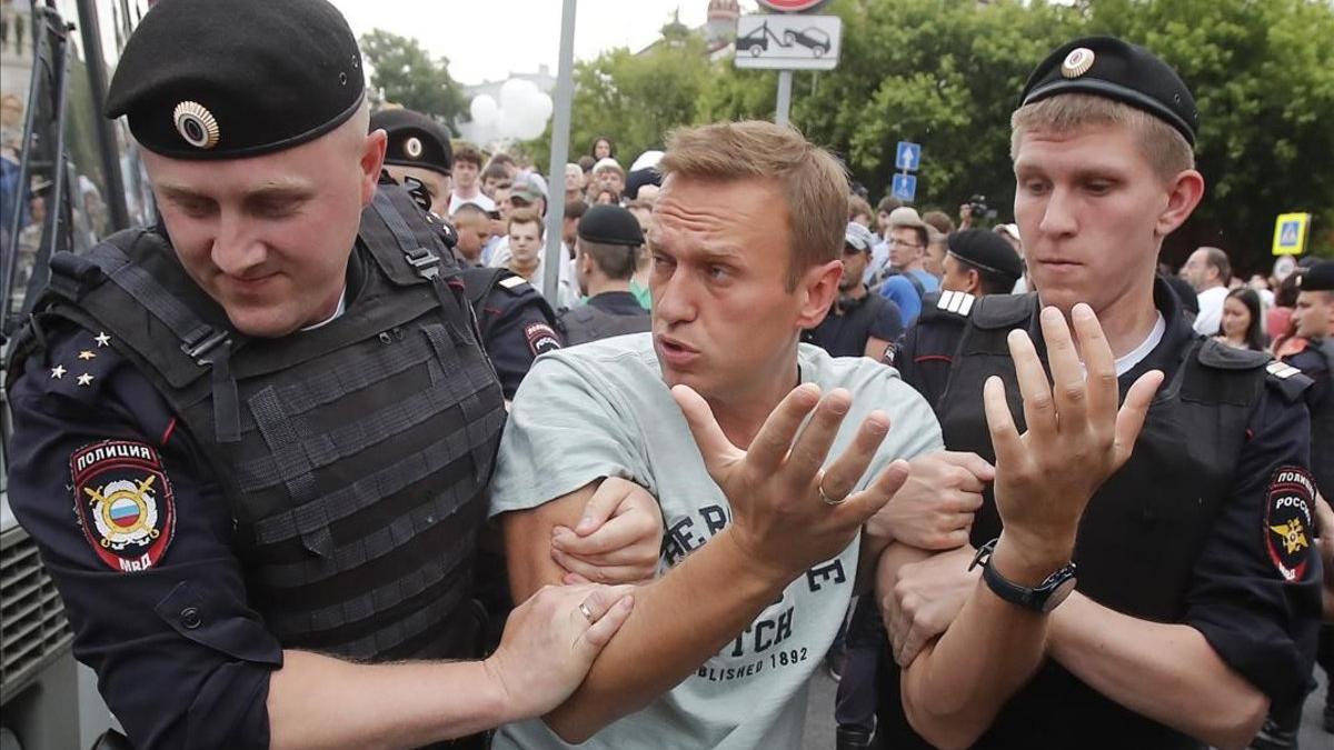 Dos agentes detienen al líder opositor ruso Aléxei Navalny durante las protestas por la detención del periodista de investigación Ivan Golúnov, este miércoles, en Moscú.